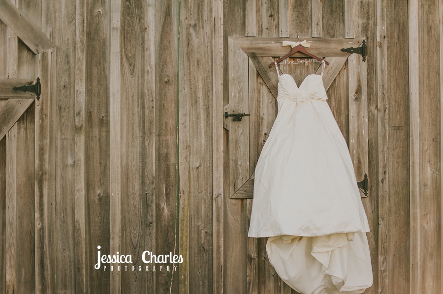 wedding dress hanging above a barn door